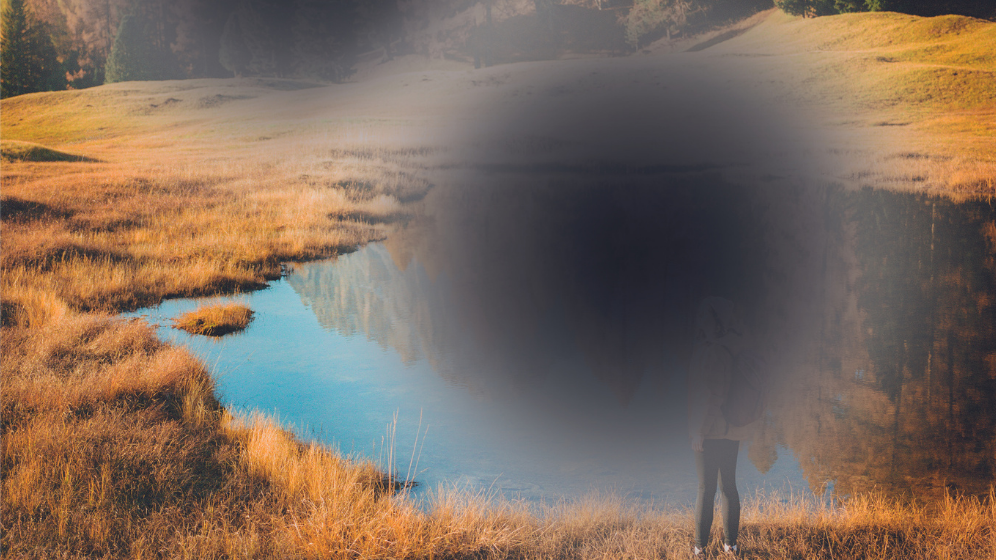 Landschaftsbild mit See und Wald und dunklen Flecken in der Mitte