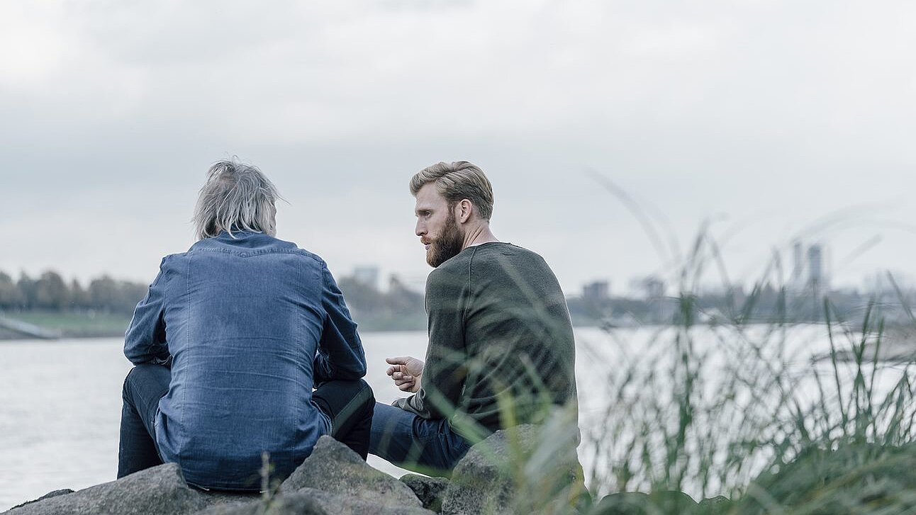 Angehörige wissen oft nicht, was eine Netzhauterkrankung bedeuten kann Vater und Sohn im Gespraech an einem Fluss