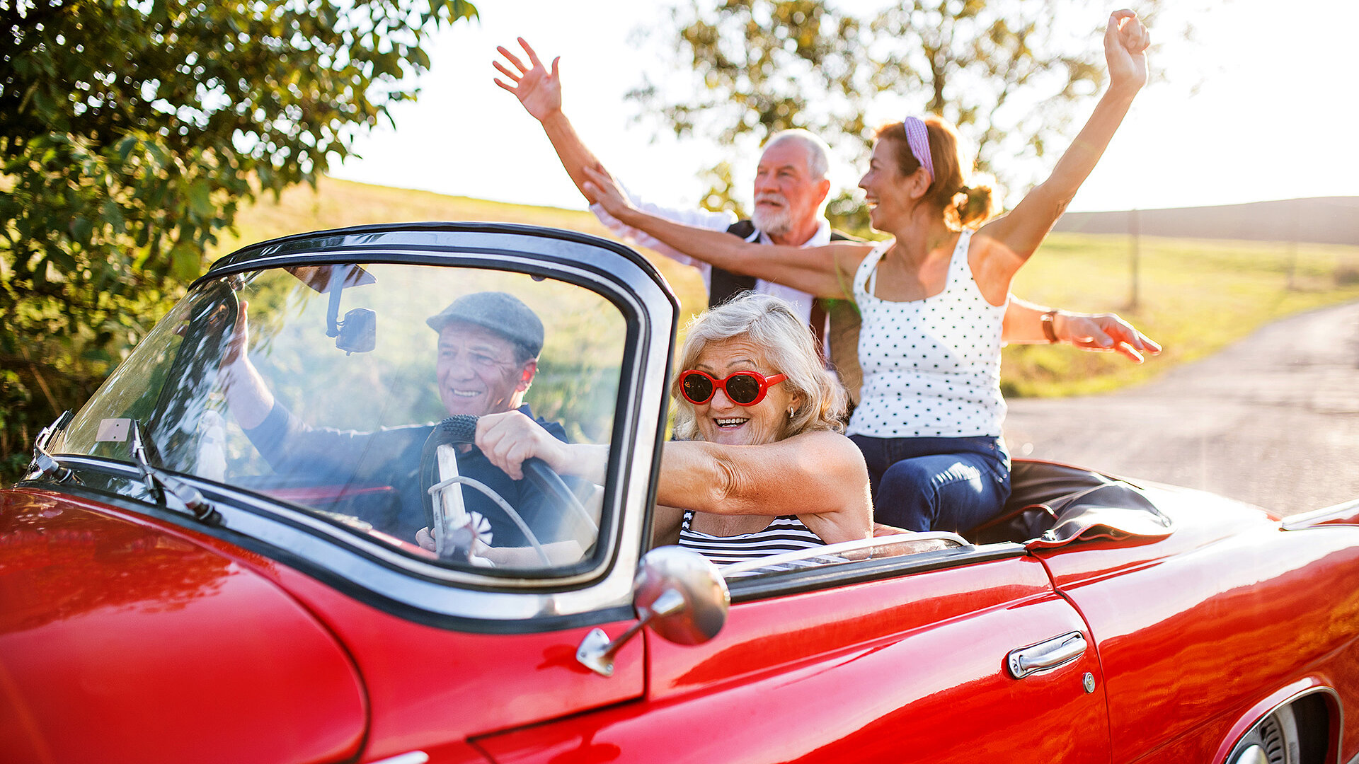 Zwei Pärchen im Cabrio Es sitzen zwei Pärchen in einem roten Cabrio und haben Spaß