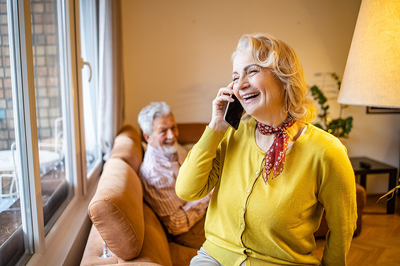 Seniorin am Telefon im Wohnzimmer 