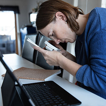 Junge Frau liest mithilfe einer elektronischen Lupe ein Dokument