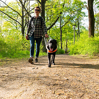 Frau mit Blindenhund im Wald