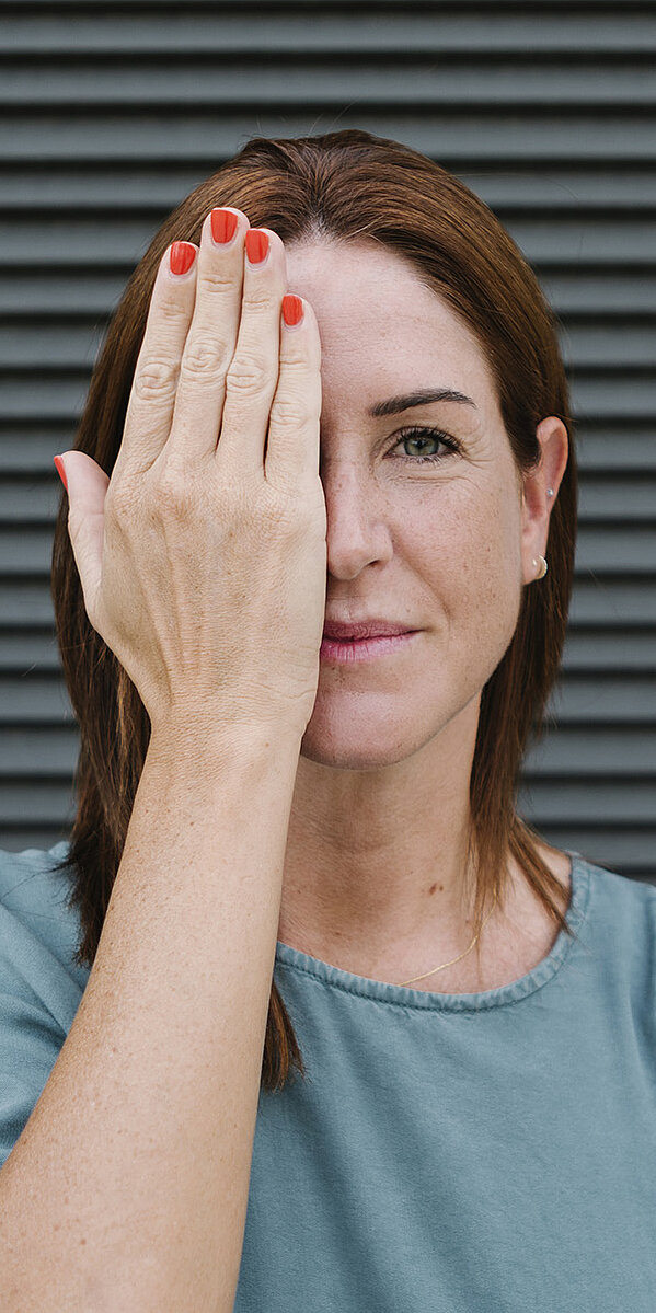 Frau hält rechtes Auge zu