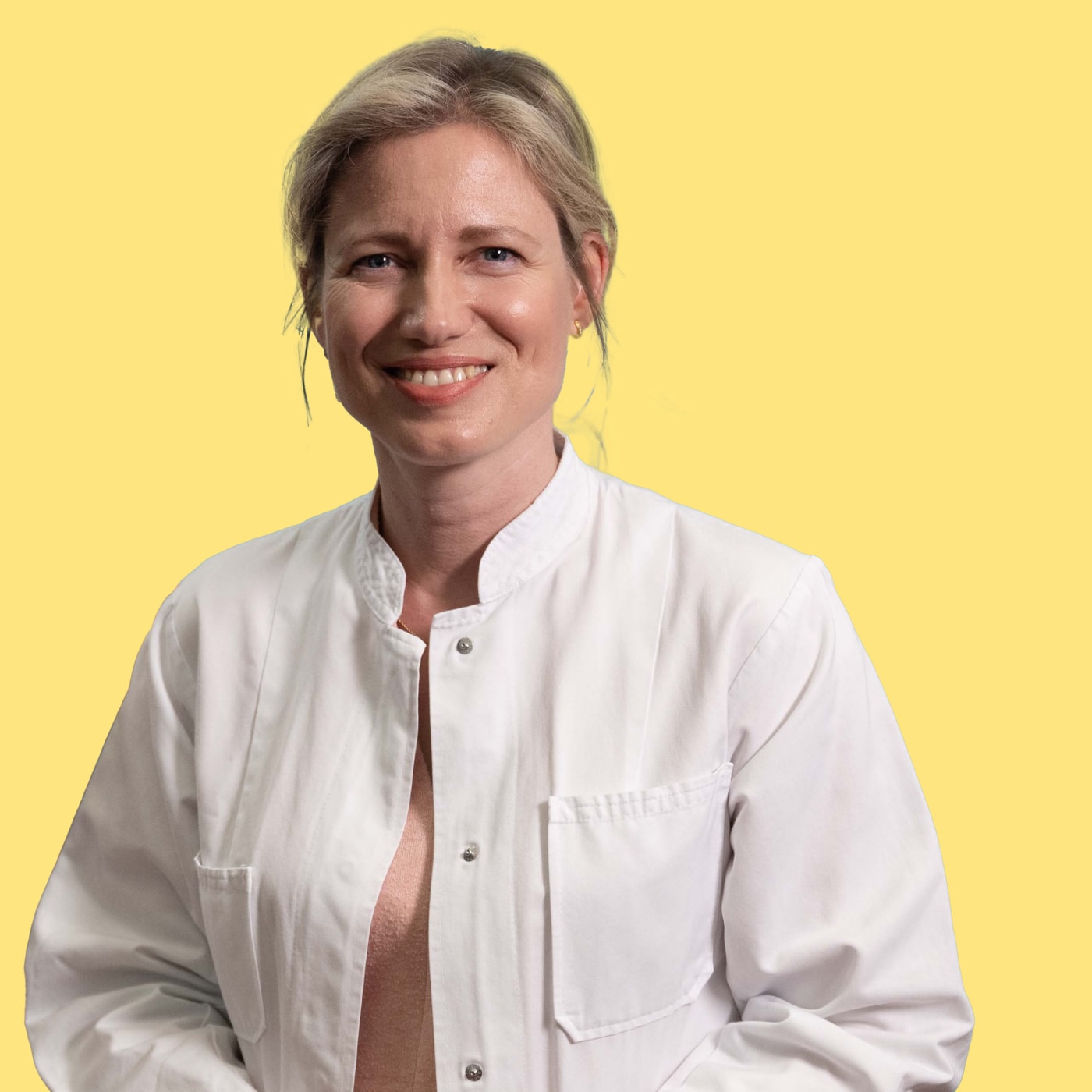 Frau in weißem Arzt-Kittel lächelt in Kamera